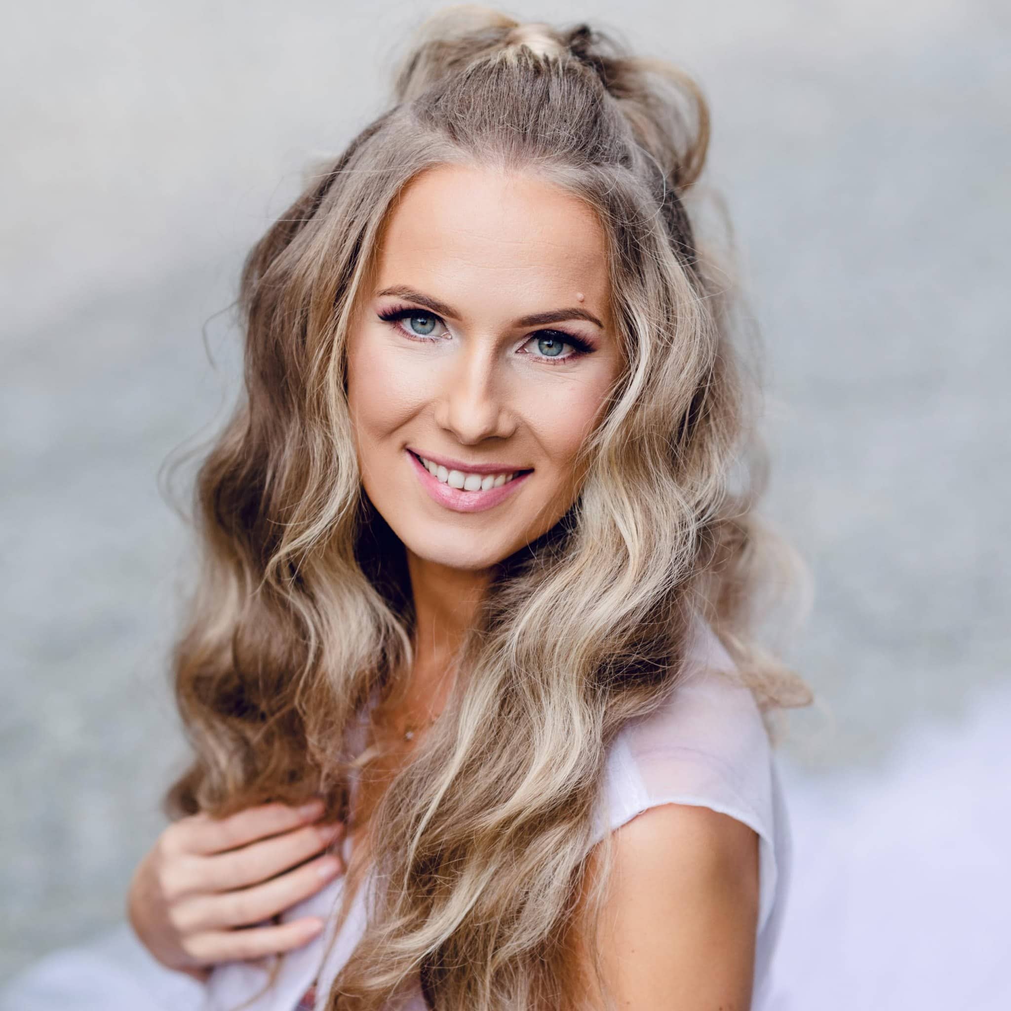 Bright smiling woman with long, wavy blonde hair outdoor.