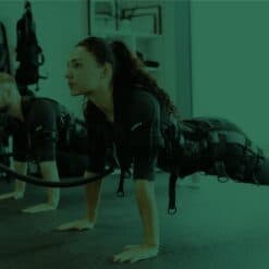 High-energy fitness class focusing on strength and endurance training with women in athletic gear performing push-ups using resistance bands.